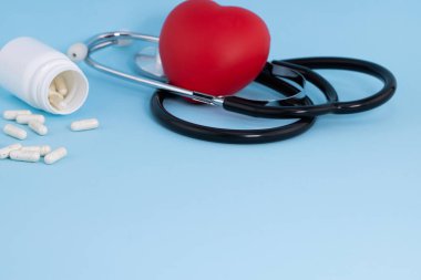 Şişeden akan beyaz ilaç ve mavi arka planda kırmızı kalp..