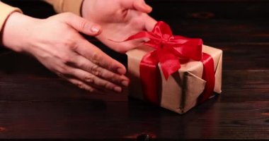 Kadın eli kırmızı kurdeleli bir hediye alır. Süper yavaş çekim.