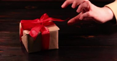 Kadının eli hediye kutusundaki kırmızı kurdeleyi çözüyor. Süper yavaş çekim.