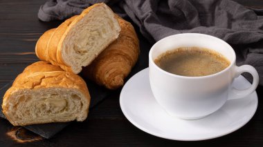 Tahta masada bir fincan kahve ve kruvasan. Üst görünüm.