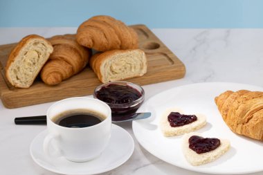 Reçelli taze kruvasan ve arka planda kahve.