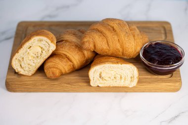 Tahtaya taze kruvasan ve reçel. Hafif arkaplanda Roissantlar.