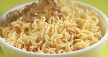 Anında erişteler sarı arka planda Çin yemek çubuklarıyla karıştırılır. Süper yavaş çekim.