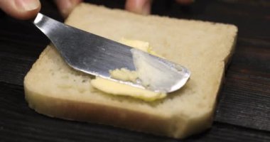 Tereyağlı ekmek. Bıçak bir dilim ekmeğe tereyağı sürüp manzarayı kapatıyor. Süper yavaş çekim.