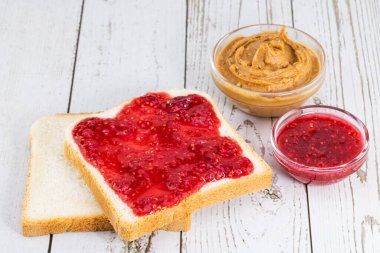 Hafif ahşap arka planda reçelli tost ve fıstık ezmesi..