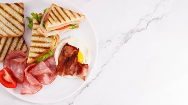 Sahanda yumurta, kızarmış pastırma, jambon ve sandviç..