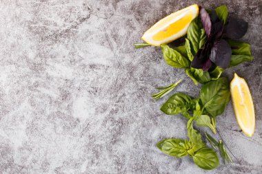 Taş zeminde bitki ve baharat seçimi. Biberiye, fesleğen ve limon. Üst görünüm.