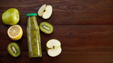 Ahşap arka planda yeşil elma ve kivi ile karıştırılmış yeşil smoothie, üst görünüm.