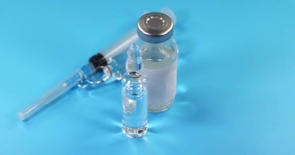 Glasfläschchen Mit Blauem Flüssigkeitsimpfstoff Und Spritze Drehen Sich Auf Blauem — Stockvideo