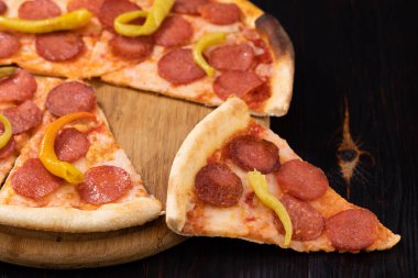 Siyah arka planda bir dilim pepperoni pizza..