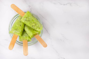 Kasede dondurulmuş kivi suyu. Çubukta buzlu şeker. Üst görünüm, alanı kopyala.