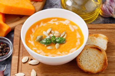 Balkabağı ve havuç çorbası kremalı ve kabak tohumlu ahşap arka planda.