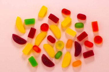 Renkli jöleli şekerler ve marmelat pembe arka planda..