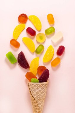 Waffle konisi ve renkli şekerler ve pembe arka planda tatlılar, üst manzara .