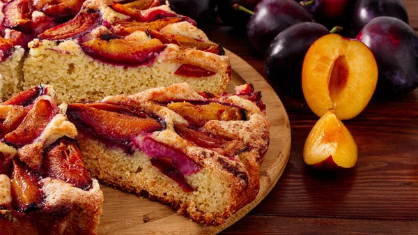 plum cake and plums on wood background.