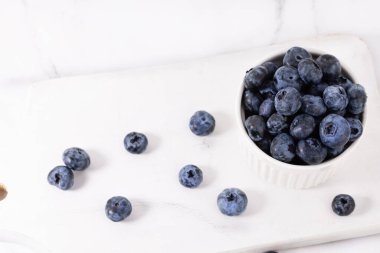 Beyaz tahta üzerinde bir kasede yaban mersini.