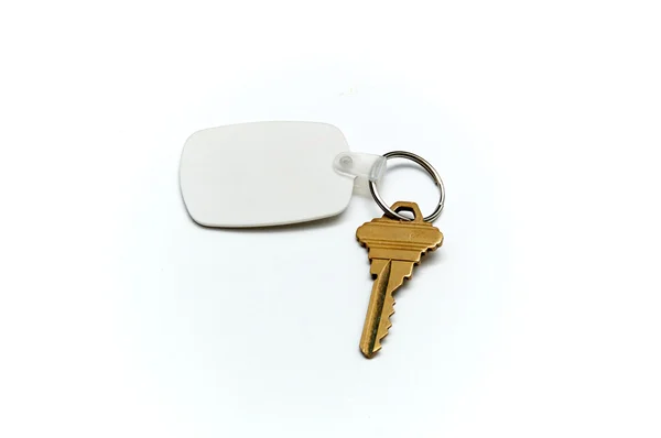 Ключ от дома и брелок поверх белого — стоковое фото