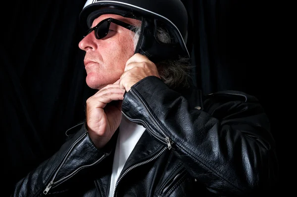 Biker in leather jacket and sunglasses adjusting helmet — Stock Photo, Image