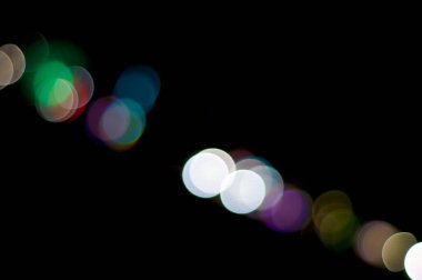 Bir sıra odak dışı renkli ışık gece gökyüzünü oluşturan bir açıyla yuvarlak şekil tasarımı oluşturur.