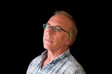 Yakışıklı, olgun, sarı saçlı, mavi gözlü, ekose gömlekli, siyah çerçeveli gözlüklü bir adamın stüdyo portresi..