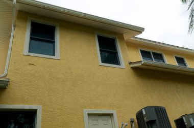 Güneybatı Florida 'daki tipik bir binanın ikinci katına bakıyorum. Pencereli sarı beyaz bir bina.