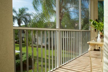 Florida 'da yüksek katlı bir dairenin balkonunda ikinci katta palmiye ağaçları ve binalar görülüyor.