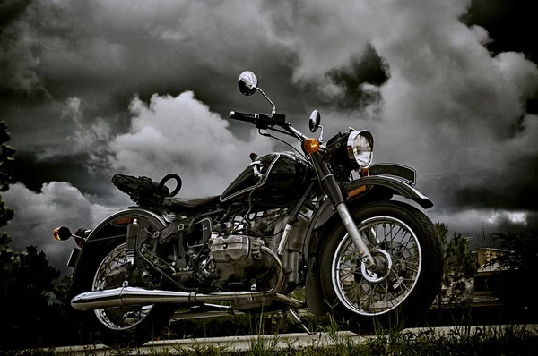 Vintage motorfiets onder storm wolken Stockafbeelding