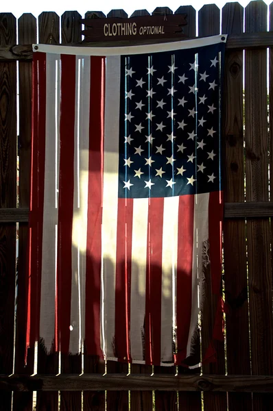Tattered american flag on fence — Stock Photo, Image