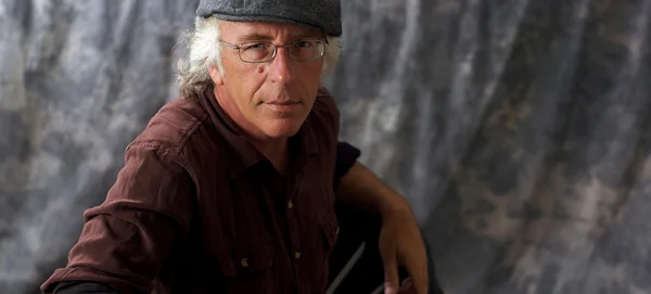 Blue eyed man with glasses and grey hair wearing cap — Stock Photo, Image