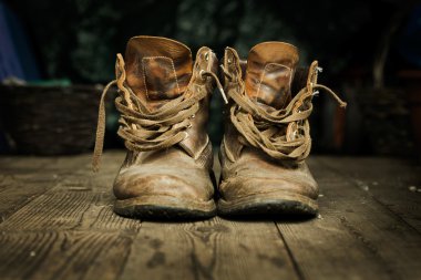 Pair of old boots on wooden floor boards. clipart