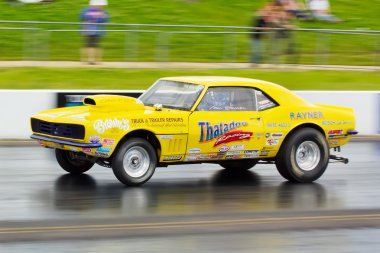 Yellow American muscle car on a drag strip clipart