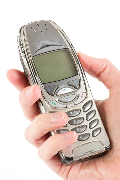 Een oude versleten mobiele telefoon wordt gehouden over Wit — Stockfoto