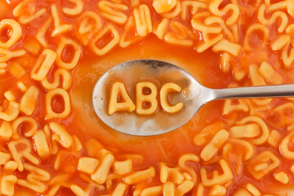 Lettere ABC a forma di pasta in salsa di pomodoro su un cucchiaio — Foto Stock