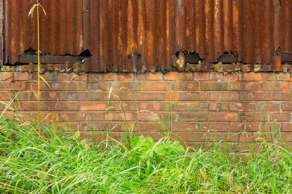 Sfondo di ferro ondulato arrugginito e muro di mattoni di fronte g — Foto Stock