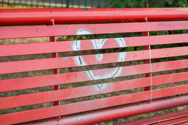 A silver heart painted on a red bench — Stock Photo, Image