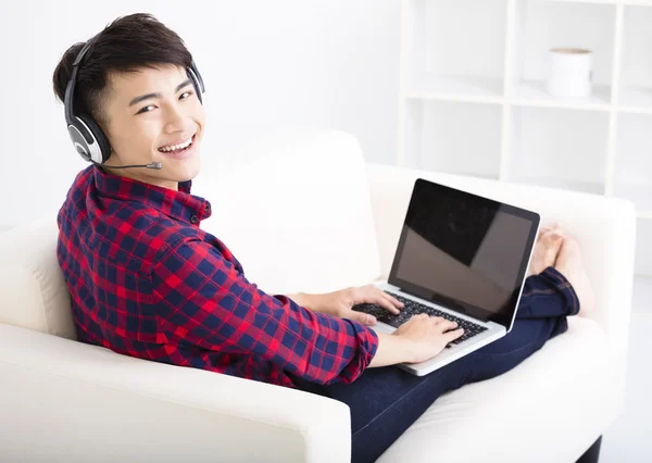 Knappe jonge man met een laptopcomputer met headset — Stockfoto