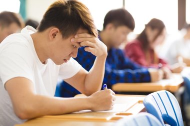 Stressed college student  for exam in classroom clipart