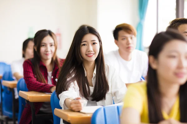 Leende kvinna collegestudent sitter med klasskamrater — Stockfoto