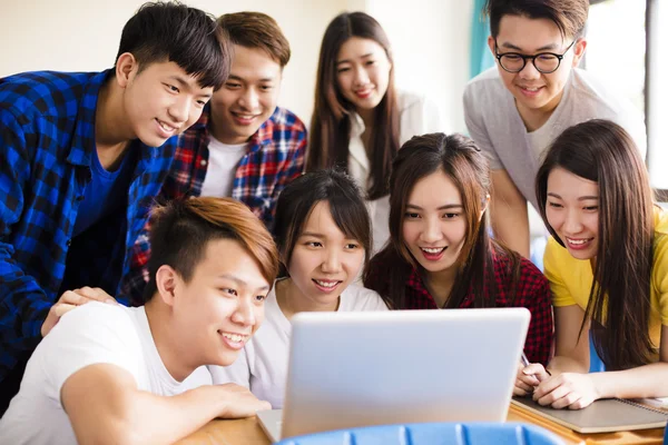 Grupo de estudiantes universitarios viendo la computadora portátil en el aula — Foto de Stock