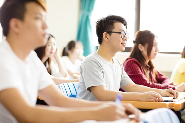 Sonriente estudiante universitario masculino sentado con compañeros de clase — Foto de Stock