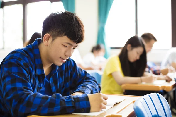 Grupo de jóvenes estudiantes que escriben notas en el aula — Foto de Stock