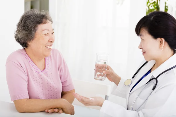Doctor giving medication and water to senior woman — Stock Photo, Image