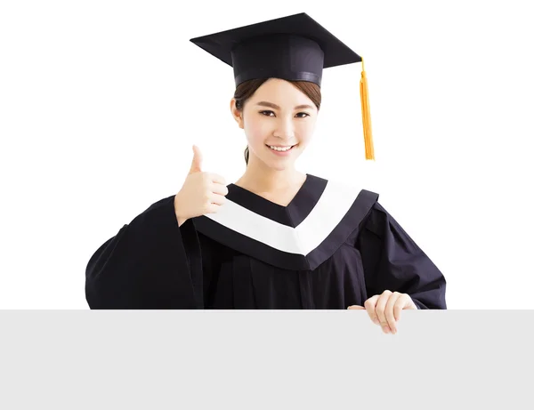 Happy female graduate showing   blank board with thumb up — Stock Photo, Image