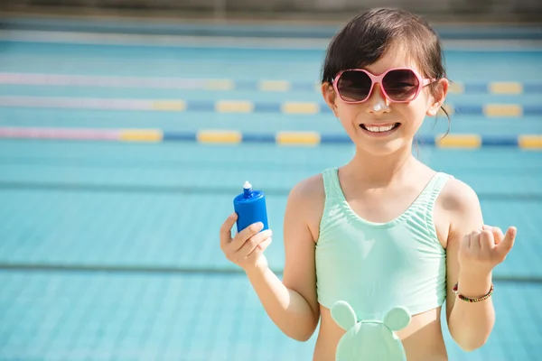 Happy little girl applying sunscreen lotion on nose — Stock Photo, Image