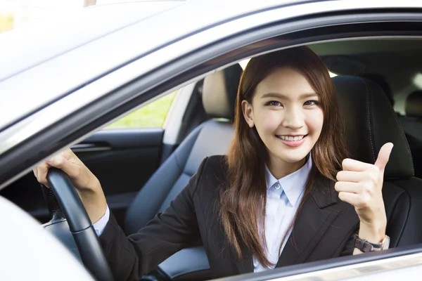 Jonge zakenvrouw zitten in auto en duimen opdagen — Stockfoto