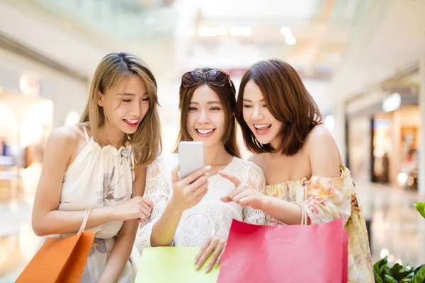 Feliz jovem mulher assistindo telefone inteligente no shopping — Fotografia de Stock