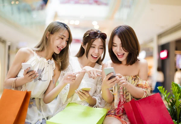 Щаслива молода жінка дивиться смартфон у торговому центрі — стокове фото