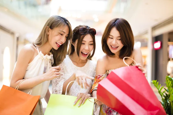 Překvapené mladé ženy při pohledu na nákupní tašky — Stock fotografie