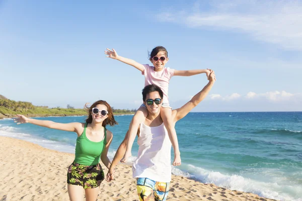 Glad ung familj promenader på stranden — Stockfoto