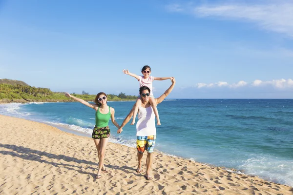 Glad ung familj promenader på stranden — Stockfoto